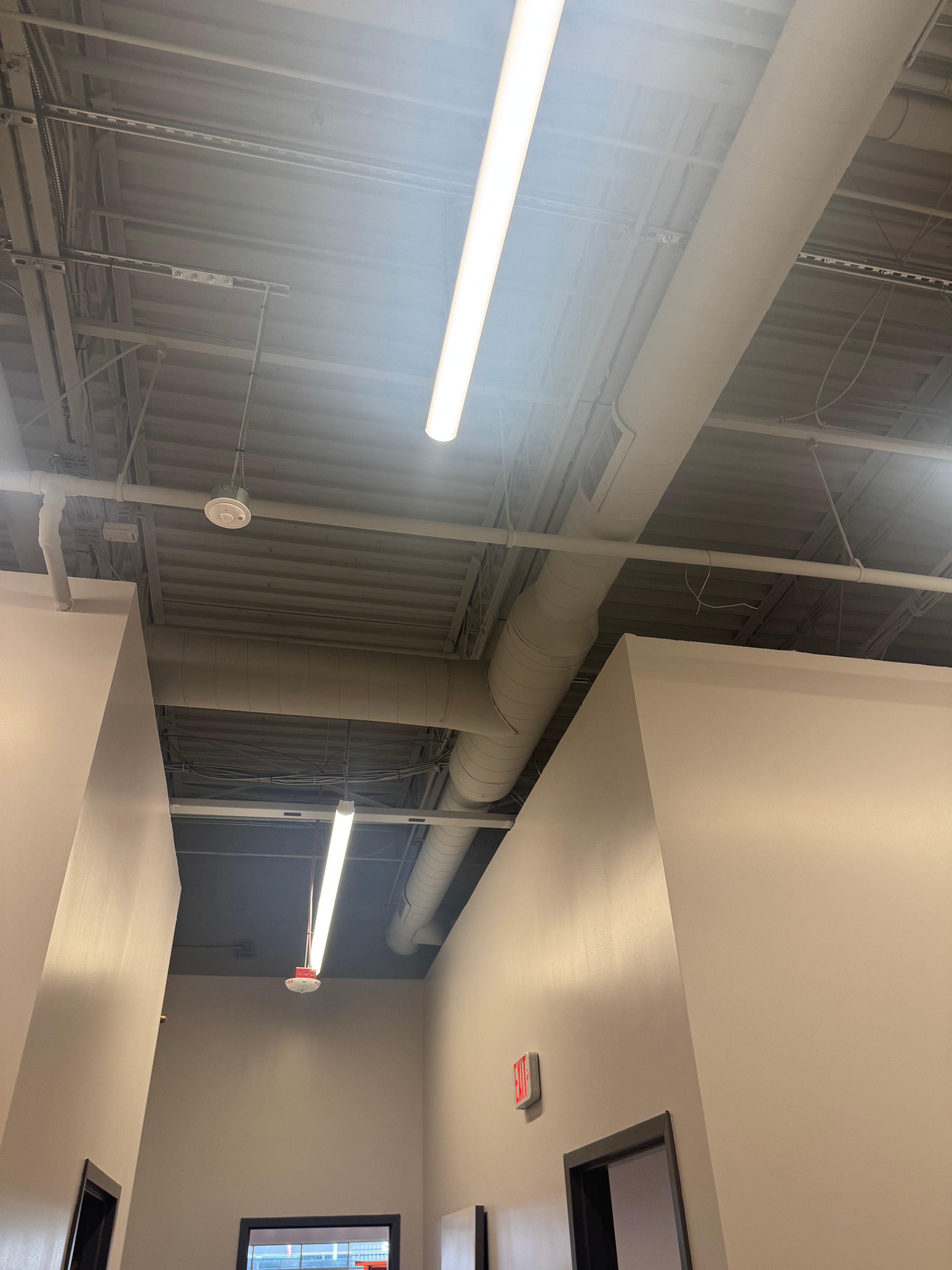 Finished retail ceiling — painted spiral round mains and track lighting